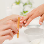 Close up of beautician filing female clients nails at spa beauty salon