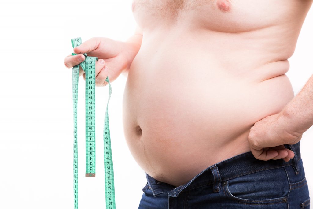 Overweight man with fat folds holding green centimeter tape in his hand closeup isolated on white background. Obesity concept